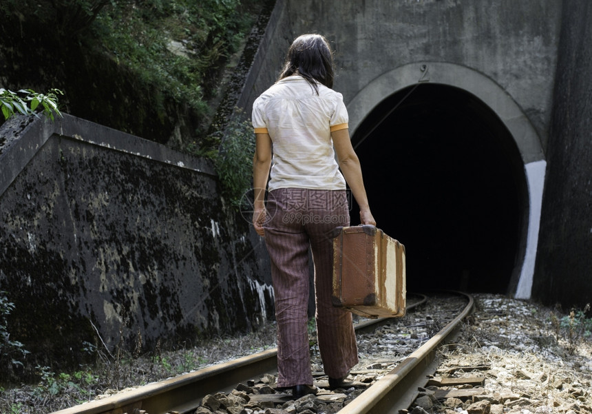 铁路公和隧道上的女用旧手提箱和图片