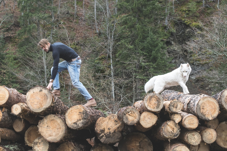 年轻男子和狗在森林的原木上时尚风格图片