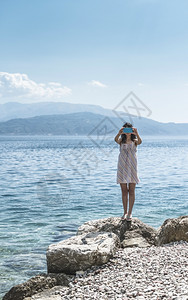 女人在海滩上用智能手机拍照图片