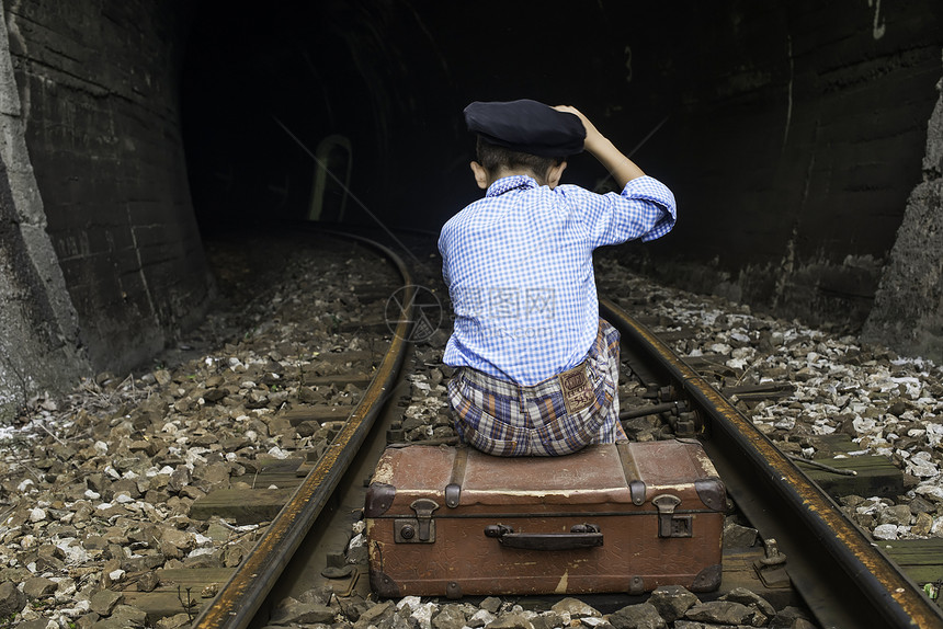 身着老式衣服的小孩坐在铁路上地道前面图片