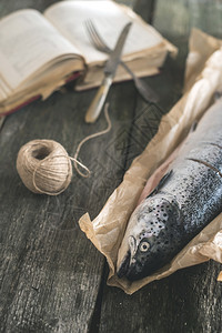 旧式木制桌和烹饪手册上的原始鲑鱼图片