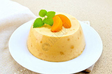 甜点pancot芝士蛋糕和白盘中的杏子在花岗岩桌背景上的餐巾纸背景图片