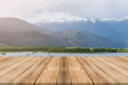 在模糊背景面前的木板空桌在森林山底的模糊湖面上看到褐色木板可以模拟显示或调换产品背景图片