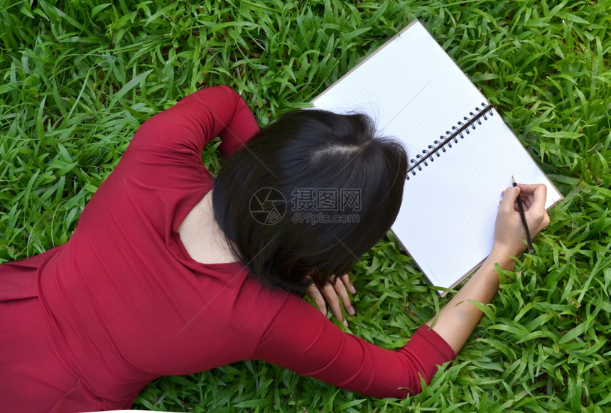 趴在草地上写作的女孩图片