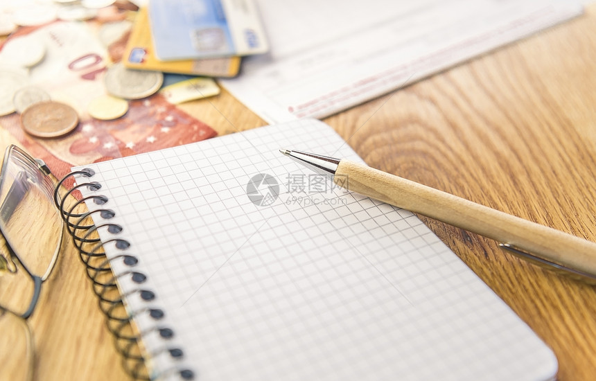 规划和组织财务工作的概念图象在背景中用图表注纸笔眼镜和金钱贺卡账单来规划组织财务工作图片