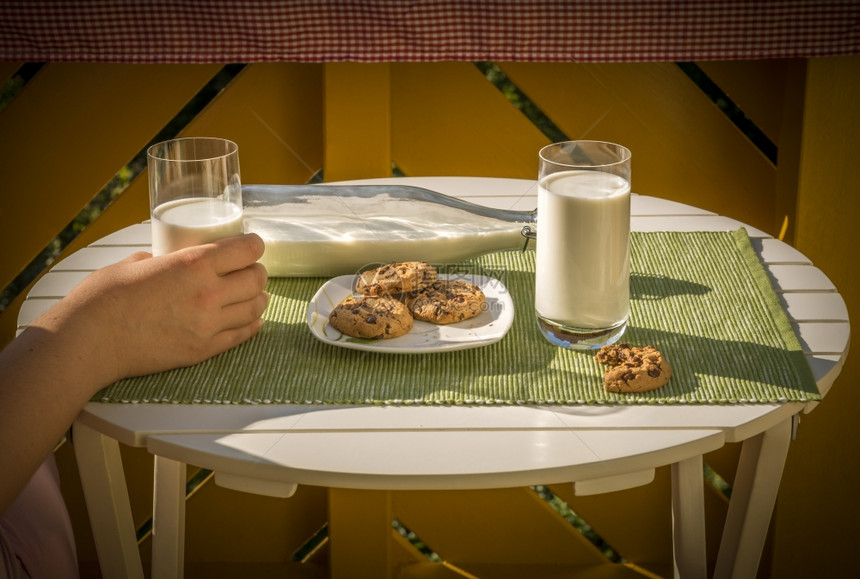 拿着牛奶的手和桌上的饼干图片
