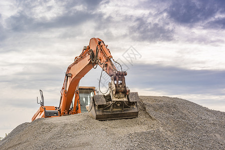 一辆橙色挖土机的前视线爬上压载物堆的顶端背景