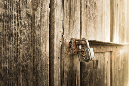 靠近一个旧木谷仓的门上的金属锁图片