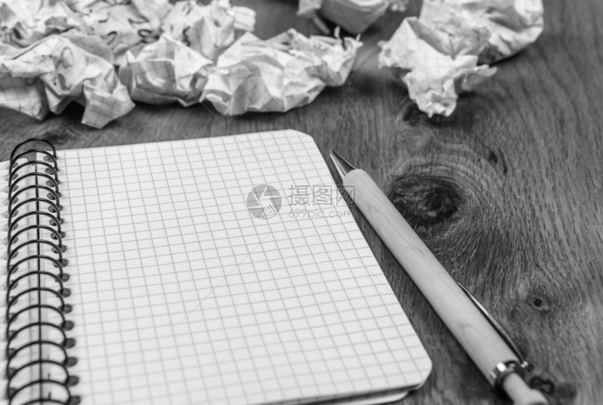 木制桌上有螺旋笔记本的概念图象周围环绕着折叠的草稿和笔图片