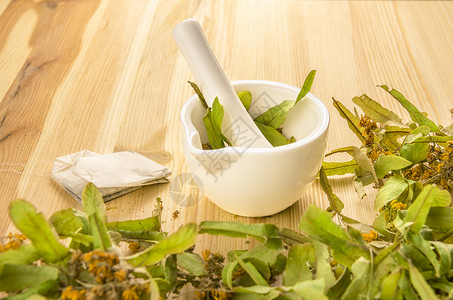 天然和有机茶叶产品概念从用迫击在木制桌上磨成圆柱花而获得的几袋茶图片