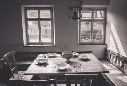古老的餐具室配有木制桌椅子和板凳旧盘餐具放在桌上图片