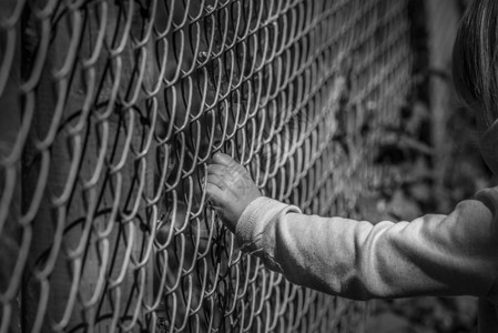 黑白一幅小女孩手抓着铁栅栏的画面图片