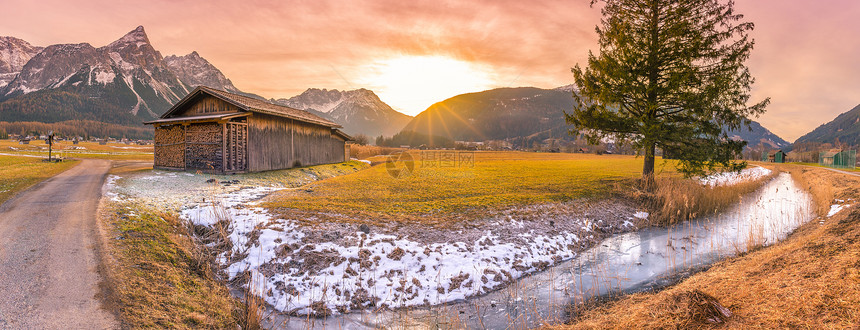 austrinlps的冬季日落在一个小austrin村的寒冬风景中黄昏时有木制谷仓冷冻河流和山丘图片