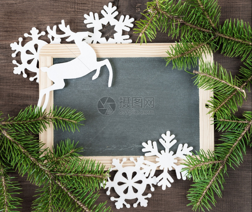 圣诞背景白黑板环绕着绿色的圆形树枝和白色的雪花鹿图片