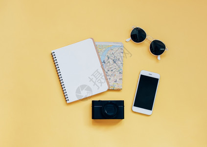 旅行项目概念黄色背景的空白笔记本照相机智能手和太阳镜顶视面风格最低图片