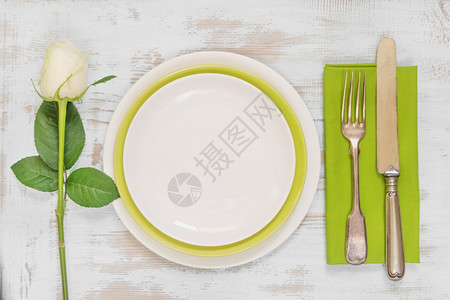 白色和绿空板纸巾旧叉刀和白玫瑰花放在旧木板桌上顶视平躺图片