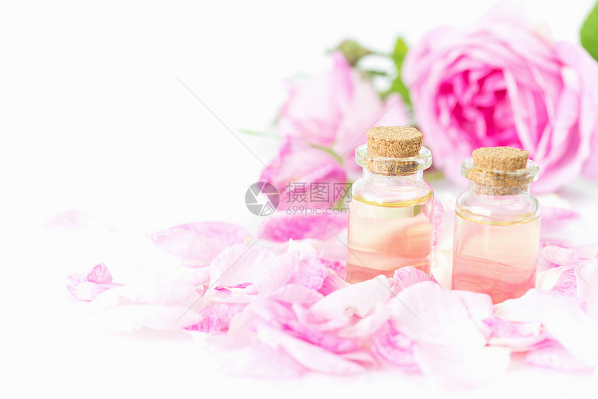 两瓶玫瑰基本油粉红玫瑰和花瓣白底孤立图片