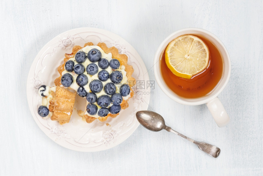 甜蛋糕蓝莓奶油和糖浆以及一杯黑茶加片柠檬顶端风景图片