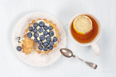 甜蛋糕蓝莓奶油和糖浆以及一杯黑茶加片柠檬顶端风景图片