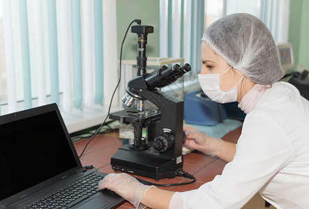 在实验室用现代电子显微镜探索生物样本的女科学家图片