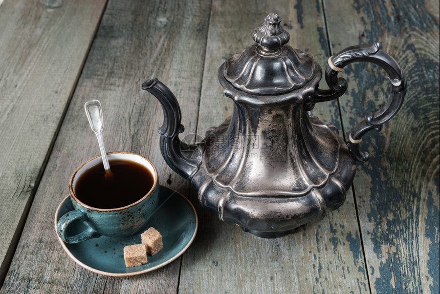 蓝色古董咖啡杯中的黑和古董旧黑木板上的银咖啡壶图片
