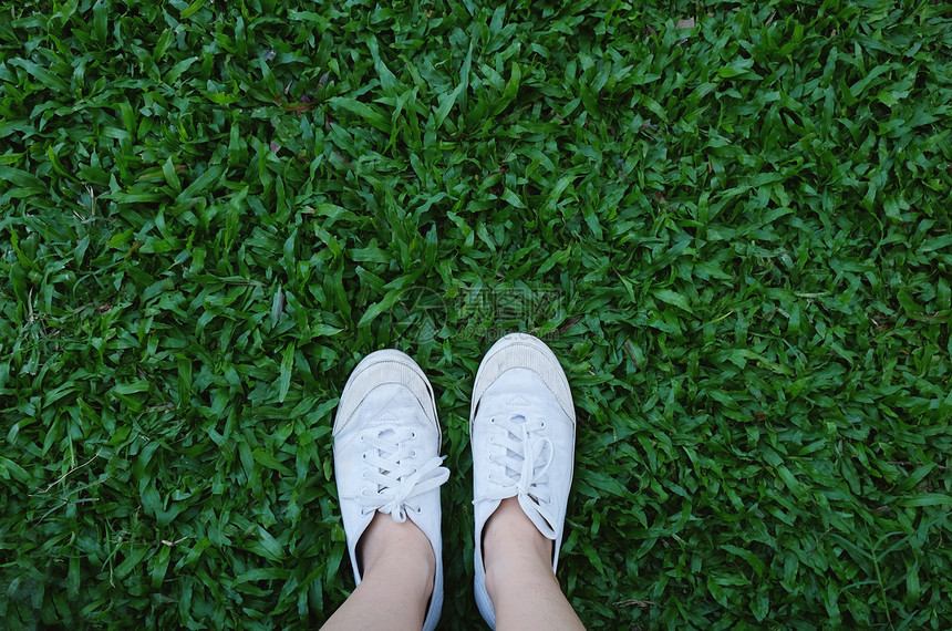 双脚穿鞋绿色草背景有复制空间春季和夏概念图片