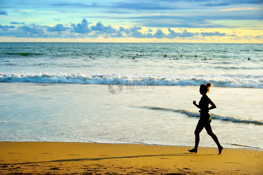 日落时在海滩上奔跑的女人图片
