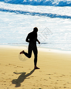 英俊男子在沙滩上奔跑侧影图片