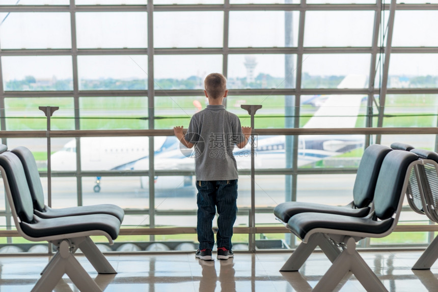 小孩在机场望着窗外看飞机图片