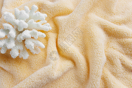 棉田橙色毛巾背景上美丽的白海珊瑚被浪压碎图片