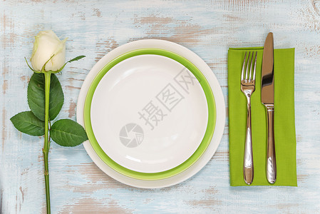 白色和绿的空板单纸巾叉刀和白玫瑰花放在旧木制桌板上顶视图平铺面视图背景图片