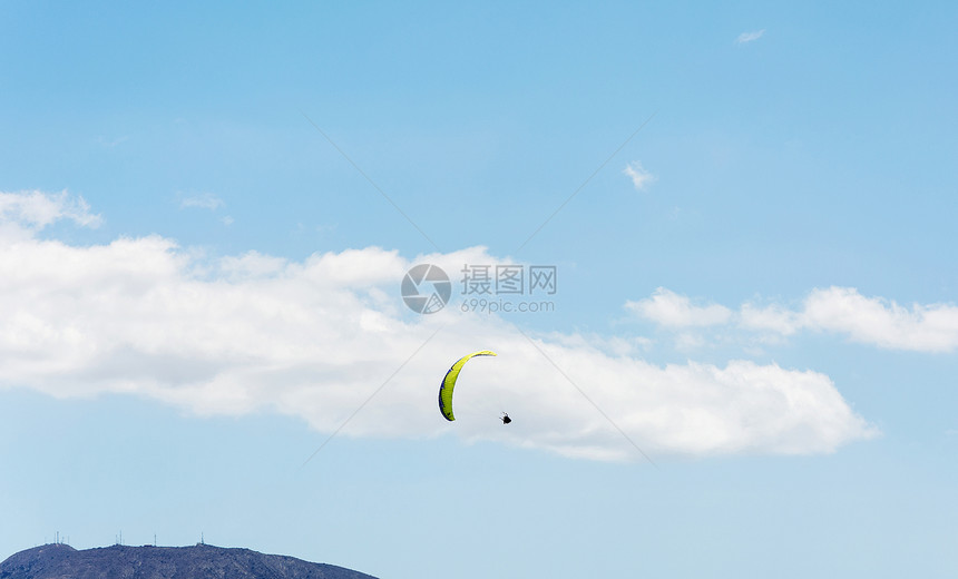 在山地和蓝天背景下云层运动员正在规划滑翔伞图片