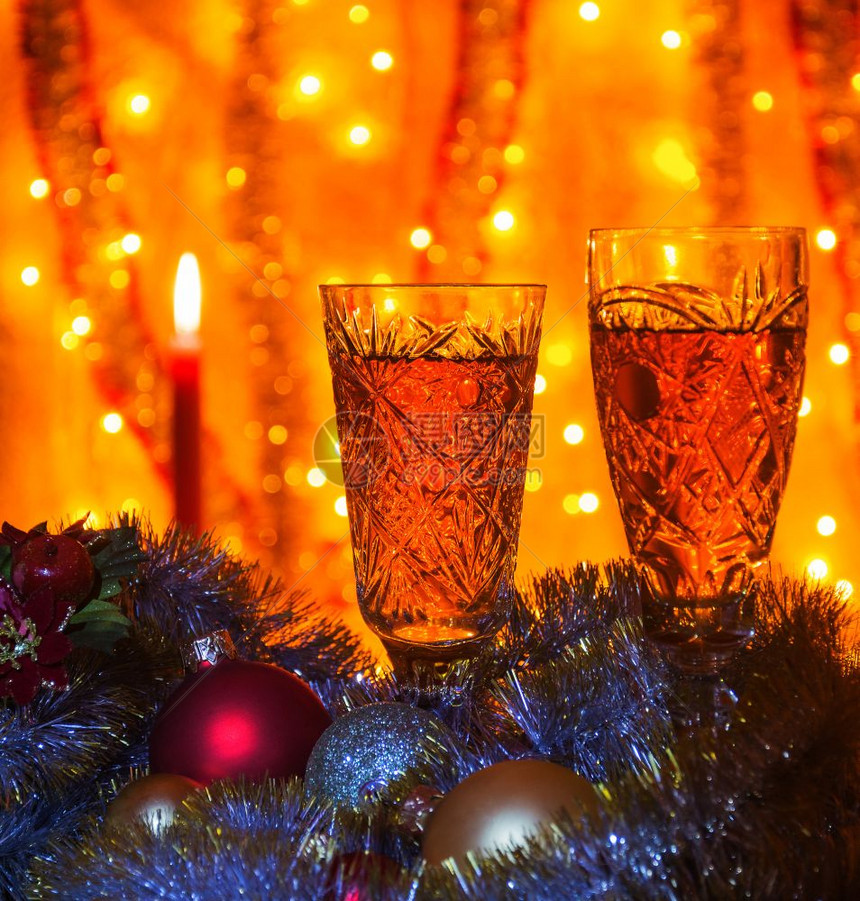 一些香槟的酒杯躺在圣诞球和罐子模糊的背景是可见燃烧蜡烛图片