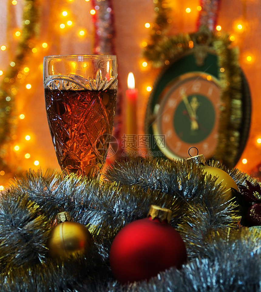前景是葡萄酒杯圣诞装饰品在花岗岩周围背景不够集中可以看到蜡烛钟时间是5分到12背景照亮了花冠图片