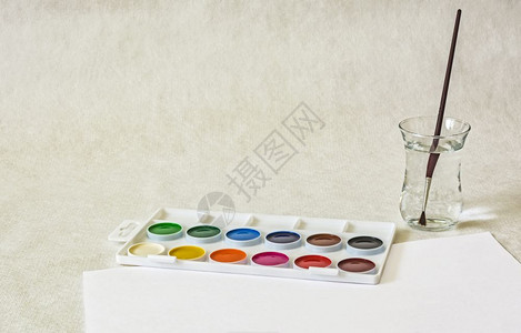 水彩一杯用刷子和白纸印在光背景上图片