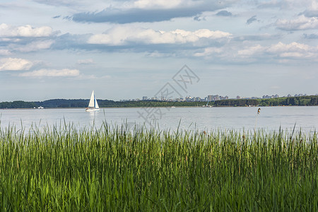 白色游艇在大湖上和地平线城市悬挂白帆图片