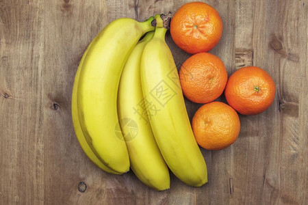 在木制表面的香蕉和橘子上背景图片