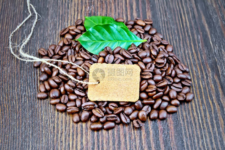 在木板背景上贴标签和绿叶子的黑咖啡谷图片