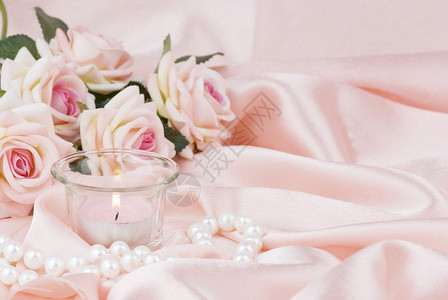 粉红玫瑰烧蜡烛和丝织上的珍珠项链背景图片