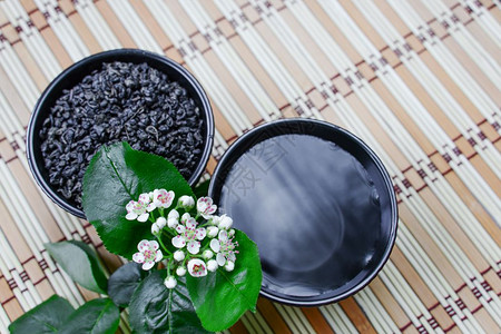 两杯陶瓷在草垫和白花上加绿茶图片