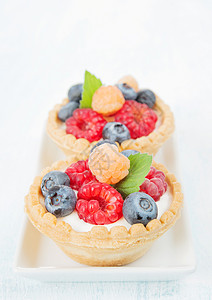 两块水果薄饼夹奶油红黄草莓和蓝放在白色瓷板的长方形上紧闭图片