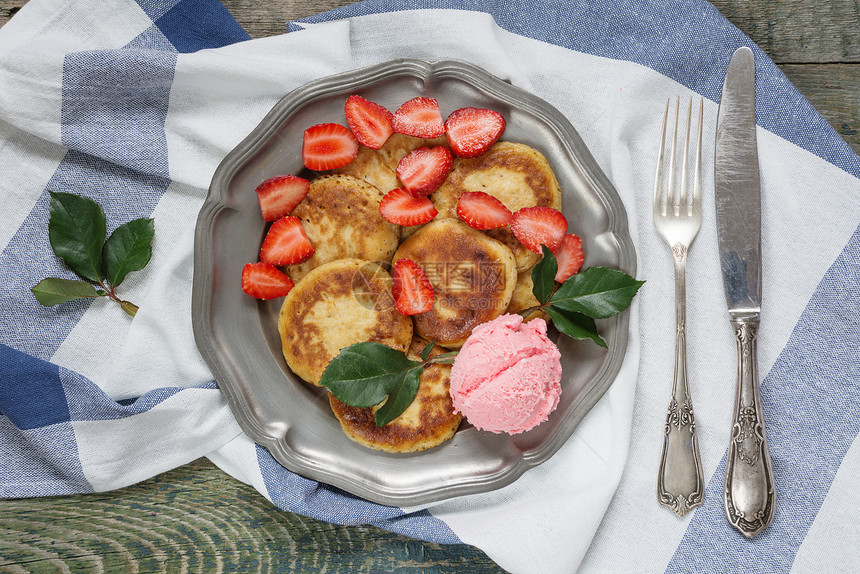 盛夏早餐煎饼加冰淇淋和成熟的草莓放在古董锡板上用旧刀和叉子顶视图片