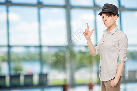 严重女孩拿着手指,在办公室戴黑帽子图片