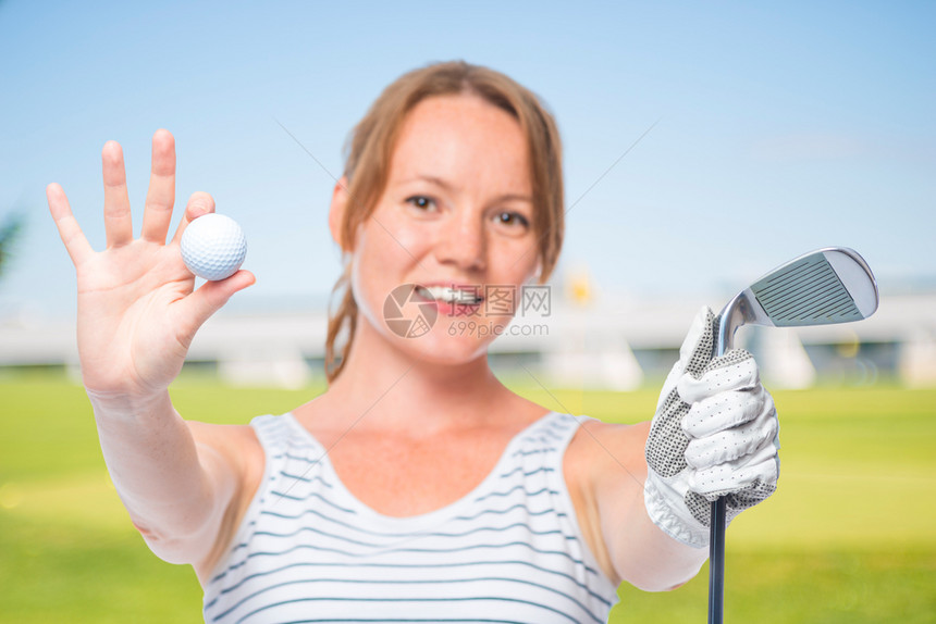 笑的姑娘在舞会上展示了相机和白背景的高尔夫俱乐部图片
