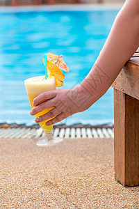 女手握鸡尾酒照片在泳池背景上高清图片