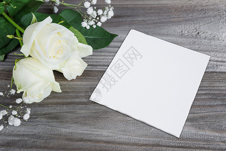 白玫瑰花束和白纸卡在旧木板的灰色背景上有文字空间图片