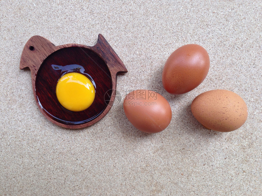 木鸡形状盘子的蛋黄和生鸡蛋图片