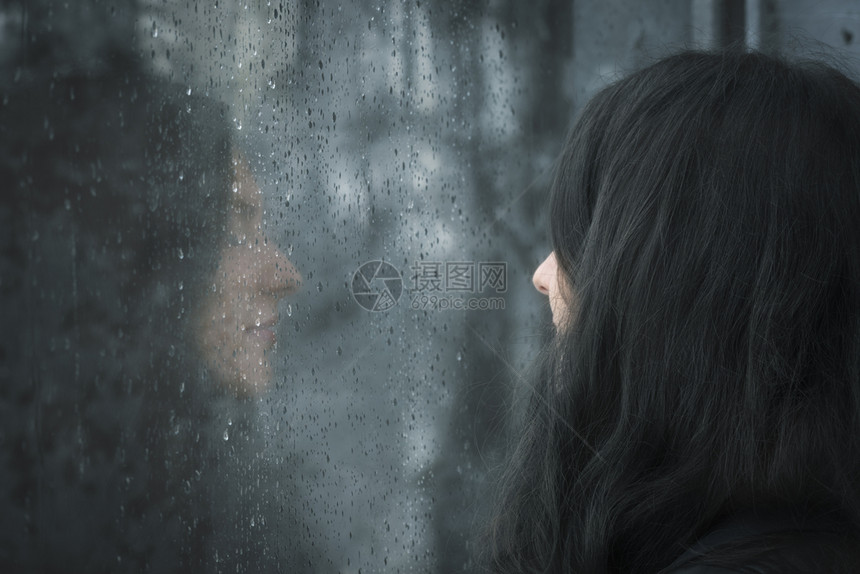 一位闭着眼睛在雨窗前思考的年轻黑发女人画面图片