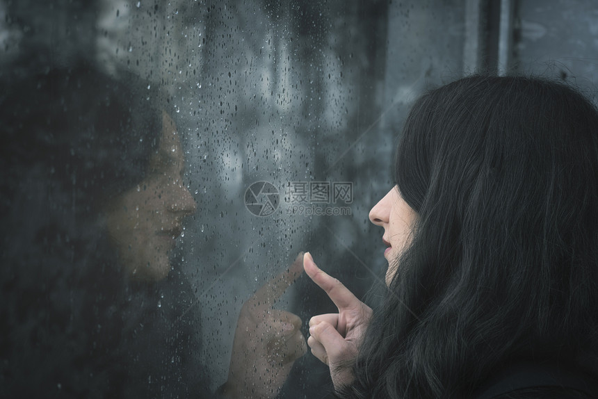 女人用手指摸着雨窗图片