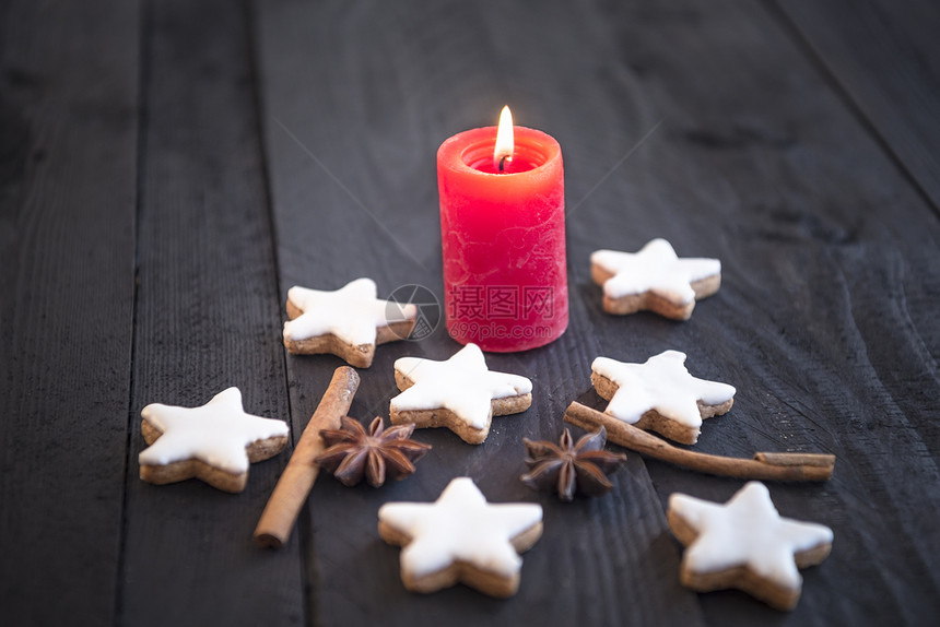 冬季传统肉桂和坚果饼干自制恒星形状在烛光下旧木制桌子上装饰香料图片